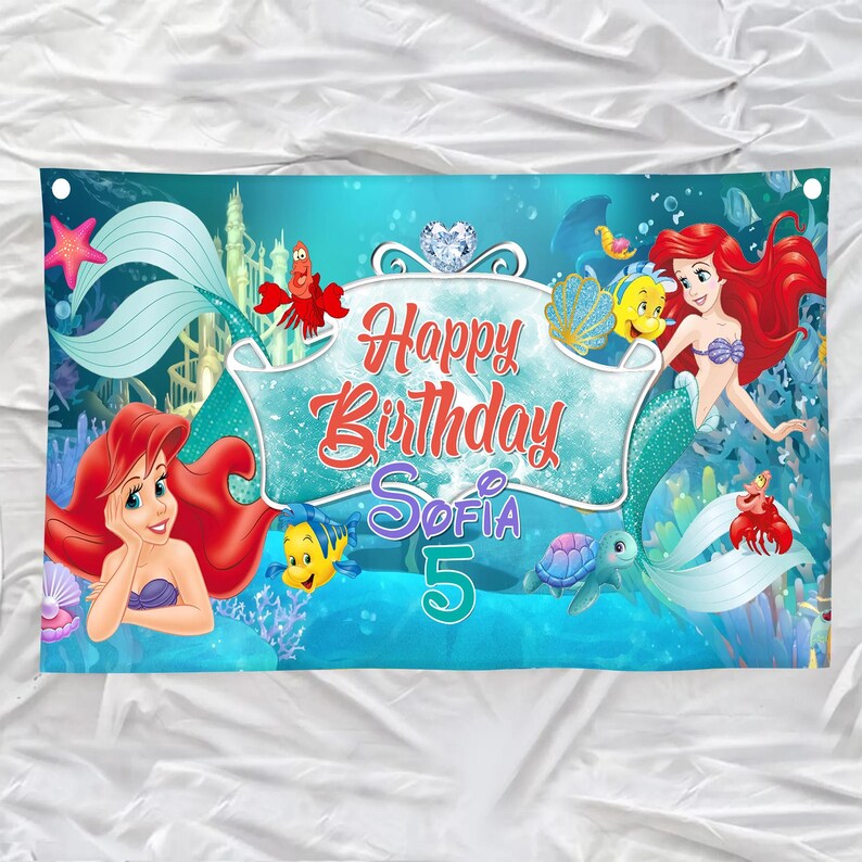 Puede incluir: Una pancarta de cumplea&ntilde;os rectangular con una escena submarina que muestra una sirena, un pez amarillo, un cangrejo rojo y una tortuga marina. El centro muestra el texto Happy Birthday Sofia 5 en letras rojas y moradas sobre fondo azul.