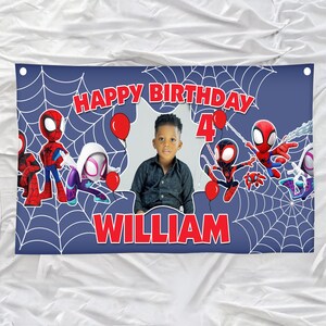 Puede incluir: Una pancarta de cumplea&ntilde;os rectangular azul con un patr&oacute;n de telara&ntilde;a blanca, texto rojo que dice HAPPY BIRTHDAY, el n&uacute;mero 4 y el nombre WILLIAM. El dise&ntilde;o incluye personajes de ara&ntilde;as, globos rojos y una foto central de un ni&ntilde;o.