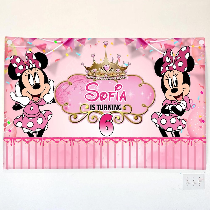 Op de afbeelding: Roze banner met Minnie Mouse-personages en de tekst "Sofia wordt 6". Minnie Mouse draagt een roze polkadotjurk en strik. De banner heeft een gouden kroon en roze accenten.