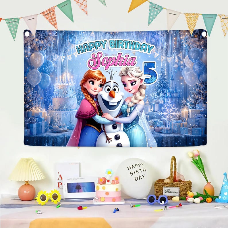 May include: A birthday banner featuring Anna, Elsa, and Olaf from Frozen, with the text "Happy Birthday Sophia 5". The backdrop is a winter scene with a castle, snowflakes, and balloons. Party decorations include a cake, balloons, and flowers.