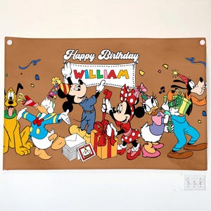 May include: A brown banner featuring Disney characters celebrating a birthday. Mickey Mouse, Minnie Mouse, Donald Duck, Daisy Duck, Goofy, and Pluto are depicted. The banner reads "Happy Birthday WILLIAM" in white lettering.