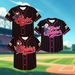 May include: Three baseball jerseys with Spiderman graphics. The jerseys are black with red vertical stripes and feature the words "Spin", "Spidey", and "Ghost Spider" in red and pink. The jerseys have white collars and cuffs.