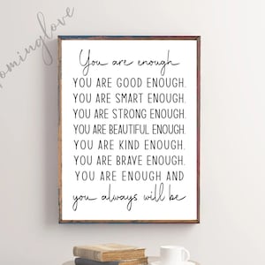 May include: A framed print with a white background and black text that reads "You are enough. YOU ARE GOOD ENOUGH. YOU ARE SMART ENOUGH. YOU ARE STRONG ENOUGH. YOU ARE BEAUTIFUL ENOUGH. YOU ARE KIND ENOUGH. YOU ARE BRAVE ENOUGH. YOU ARE ENOUGH AND you always will be."
