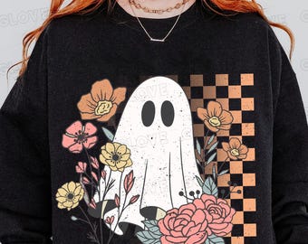 May include: Black sweatshirt featuring a white ghost graphic with black oval eyes, surrounded by colorful flowers and a checkered pattern. The word "LOVE" is printed on the ghost. A fun and festive design for Halloween or everyday wear.