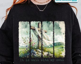 May include: Black sweatshirt with a watercolour design of a wooden cross draped with white fabric, set against a landscape with flowers and the text "It is well with my soul." The design is framed within vertical lines.
