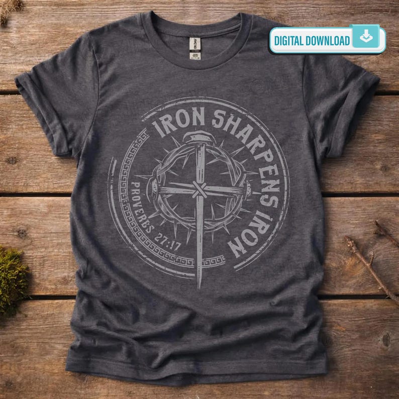 May include: Dark gray t-shirt with a circular graphic featuring a cross, crown of thorns, and the text "Iron Sharpens Iron" and "Proverbs 27:17". The shirt has rolled-up sleeves and a crew neck.