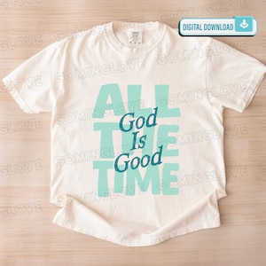 May include: Cream-colored t-shirt with the text "ALL TIME God Is Good" in a teal color. The shirt has a classic crew neck and short sleeves. The words are stacked vertically and horizontally, creating a visually appealing design.