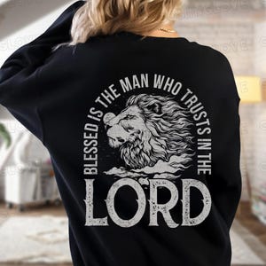 May include: Black sweatshirt with a white graphic design of a lion's head with the text "Blessed is the man who trusts in the Lord".