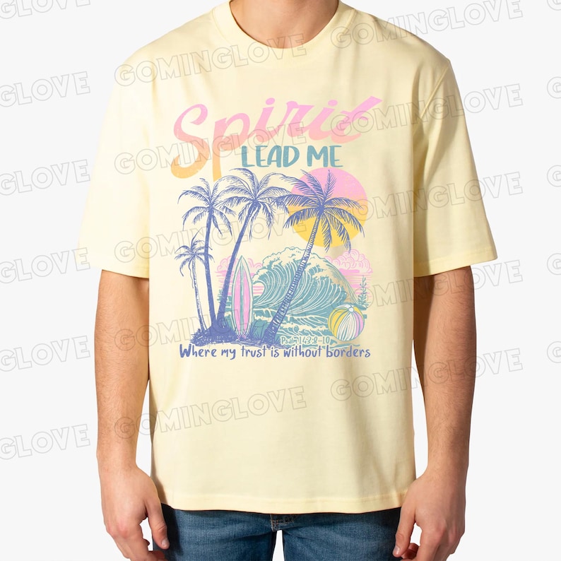 May include: A yellow t-shirt with a graphic print of palm trees, a wave, and a surfboard. The text "Spirit Lead Me" is printed in pink and blue above the graphic. The text "Where my trust is without borders" is printed in blue below the graphic.