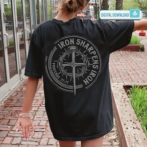 May include: Black t-shirt with a circular graphic on the back. The graphic features a cross, a crown of thorns, and the text "IRON SHARPENS IRON" and "PROVERBS 27:17". The shirt has short sleeves and a relaxed fit.