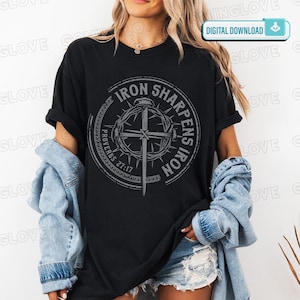 May include: Black t-shirt with a circular graphic featuring a cross, thorns, and the text "IRON SHARPENS IRON" and "PROVERBS 27:17". The shirt is worn with a denim jacket and shorts.
