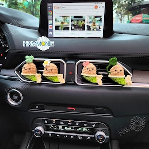 Peut inclure: Quatre diffuseurs d'air de voiture en crochet en forme de petite personne avec une tête verte feuillue. Les diffuseurs d'air sont suspendus aux bouches d'aération d'une voiture. Les diffuseurs d'air sont de couleur marron, verte et rose.