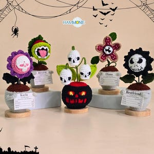 Peut inclure: D&eacute;corations de plantes crochet&eacute;es sur le th&egrave;me d'Halloween. Chaque plante pr&eacute;sente un design unique, notamment un cr&acirc;ne, un monstre et un visage inspir&eacute; de Jack Skellington. Les plantes sont dans de petits pots avec des socles en bois.