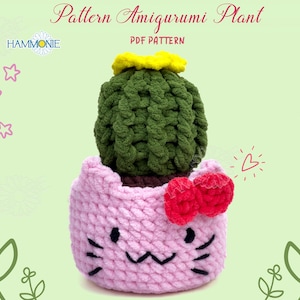 May include: A crochet amigurumi cactus plant in a pink cat-shaped pot with a red bow. The cactus is green with a yellow flower on top. The pattern is available as a PDF download.