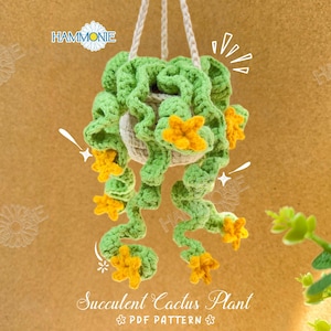 May include: A handmade, hanging crochet succulent cactus plant. The plant features green, curly leaves and yellow flowers. The plant is suspended by a white rope and is in a beige pot. The text "Succulent Cactus Plant" is at the bottom.