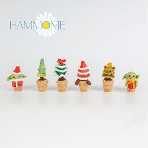 May include: A set of six crocheted Christmas tree decorations. The trees are in different colours and styles, including green, red, and white. The decorations are in small pots and are perfect for decorating a Christmas tree or adding a festive touch to your home.