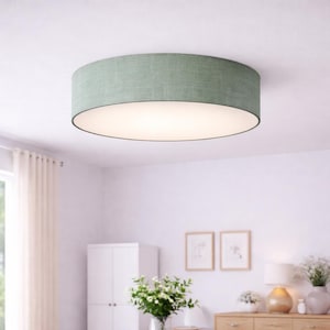 Può includere: Una plafoniera rotonda verde chiaro. La lampada ha un paralume in tessuto e un interno bianco, che fornisce un'illuminazione ambientale soffusa. L'apparecchio è montato su un soffitto bianco, adatto all'arredamento della casa.