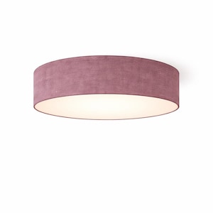 Op de afbeelding: Een plafondlamp met een cilindrische kap in een gedempte mauve kleur. De kap heeft een textuur. Het licht straalt zacht en warm uit de binnenkant.