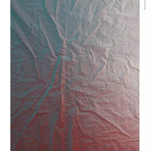 May include: A close-up of a crumpled piece of paper with a gradient of blue and red colors. The paper is folded and creased, creating a textured surface. The text "MODERNA MUSEET" is written in black ink at the bottom of the image.