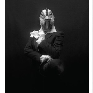 Puede incluir: Una fotografía en blanco y negro de una persona que lleva una máscara de pollo y un traje. La persona sostiene una flor y un sombrero.