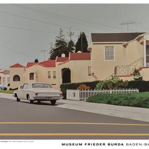 May include: A print featuring a white vintage car parked on a suburban street in front of cream-coloured houses with red roofs. The text at the bottom reads: ROBERT BECHTLE | '64 CHRYSLER | 1971 | Oil on canvas | 101.6 x 152.4 cm | MUSEUM FRIEDER BURDA BADEN-BADEN.