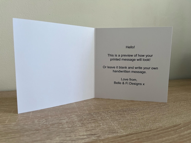 Pode incluir: Cart&atilde;o de felicita&ccedil;&otilde;es branco aberto com texto que diz "Ol&aacute;! Esta &eacute; uma pr&eacute;-visualiza&ccedil;&atilde;o de como a sua mensagem impressa ficar&aacute;!" e "Love from, Belle & Fi Designs x."