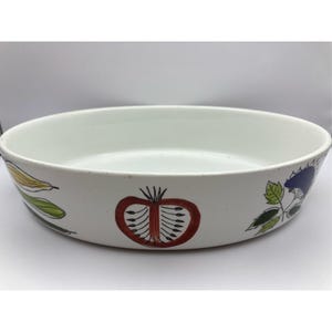 Könnte beinhalten: Ovale Servierschale aus weißer Keramik mit handgemalten Gemüsemotiven. Die Schale zeigt eine rote Tomate, grüne Blätter und gelben Mais. Ein dekoratives Stück zum Servieren von Speisen.