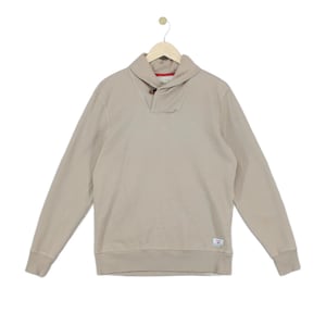 May include: A beige long-sleeve pullover sweatshirt featuring a shawl collar neckline with a single brown button closure. The garment includes a small rectangular white brand label on the lower left side and red interior trim at the collar.