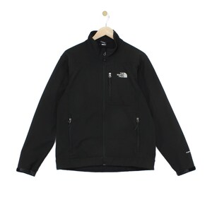May include: A black long-sleeve jacket with a high collar and a full-length front zip. The garment features two zipped side pockets and one zipped chest pocket. The North Face logo is embroidered in white on the upper left chest area.