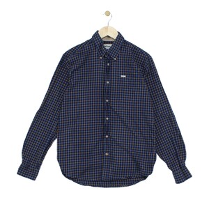 May include: A long-sleeve button-down shirt in a dark navy blue fabric featuring a grid pattern of thin yellow and white lines. The shirt includes a button-down collar, a front button placket, and a small white Barbour brand label on the chest.