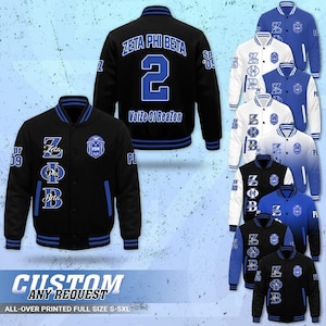 May include: A black varsity jacket featuring blue accents, the text Zeta Phi Beta, the number 2, and the phrase Voize Of Reazon. The jacket includes a circular logo, striped ribbed cuffs, and a button-up front. Additional colour variations are shown.
