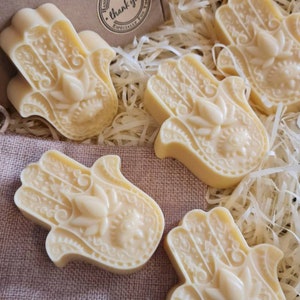 Può includere: Cinque saponette fatte a mano a forma di mano di Hamsa, un simbolo di protezione. Le saponette sono di colore giallo chiaro e hanno disegni intricati. Le saponette sono confezionate in una scatola con un adesivo "Hand Made With Love - Thank You".