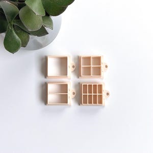 Peut inclure: Quatre contenants en plastique avec différentes configurations de compartiments. Les contenants sont beiges et ont un petit trou sur le côté pour accrocher.