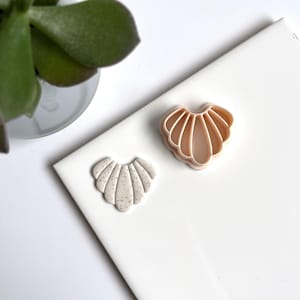 Peut inclure: Deux pinces à cheveux en forme de coquille, l'une est rose clair avec une finition lisse et l'autre est beige clair avec une finition mouchetée.