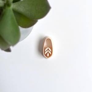 Könnte beinhalten: Eine kleine, ovale, beigefarbene Silikonform mit einem Blattdesign. Die Form ist perfekt zum Erstellen von dekorativen Akzenten für Kuchen, Kekse oder andere Backwaren.