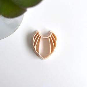 Peut inclure: Un moule en silicone rose clair en forme de collier avec un bord festonné.