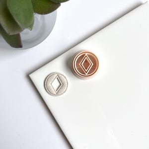 Peut inclure: Deux emporte-pièces, l'un de couleur rose clair et l'autre de couleur gris clair. Les deux emporte-pièces sont en forme de diamant.