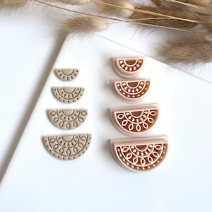 Op de afbeelding: Set van zes halve cirkelvormige kleioorbellen in twee kleuren. Drie oorbellen zijn lichtbruin met een gedetailleerd ontwerp, en drie oorbellen zijn lichtroze met een gedetailleerd ontwerp.