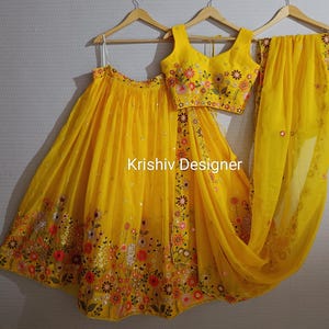 Op de afbeelding: Een gele geborduurde lehenga met een bijpassende gele geborduurde choli en dupatta. De lehenga en choli zijn geborduurd met bloemen en versierd met pailletten. De dupatta heeft een gegolfde zoom.