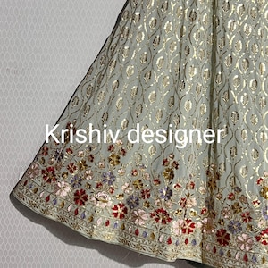 May include: A light green skirt with a floral pattern and gold sequins. The skirt has a scalloped hemline and is decorated with colourful embroidery.