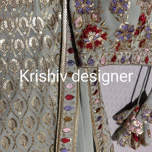 May include: A light blue embroidered fabric with gold sequins and a floral design. The fabric has a border of gold sequins and colourful embroidery. The text "Krishiv designer" is visible in the image.