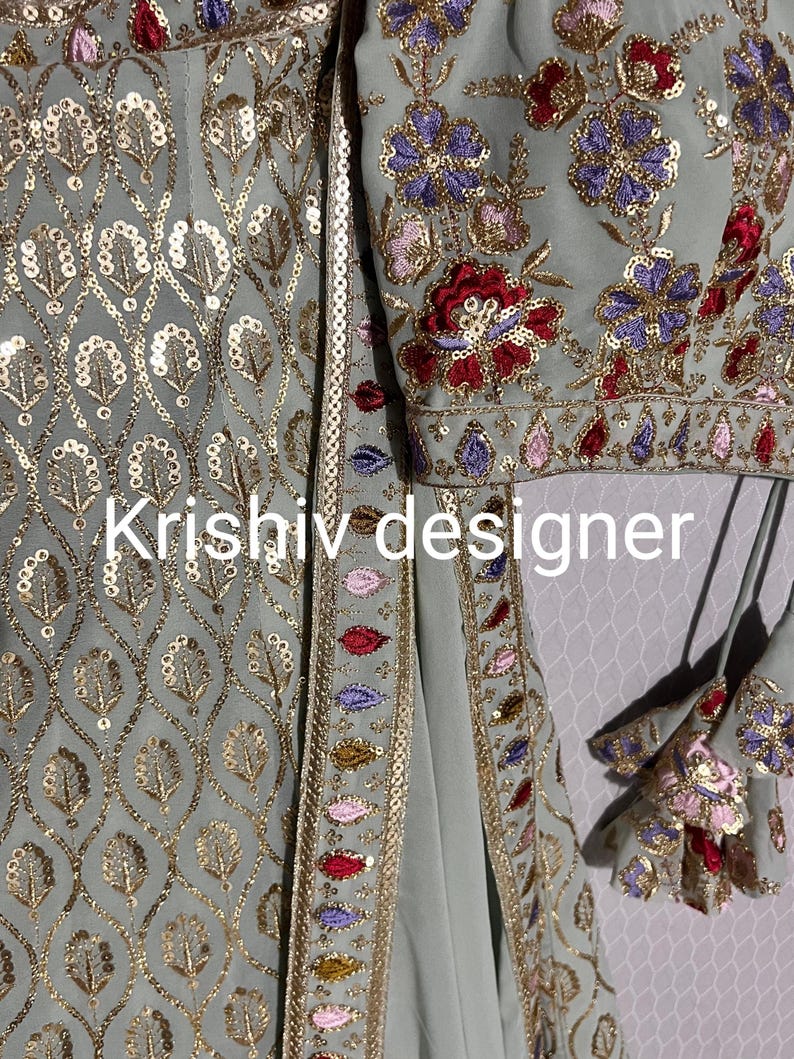 May include: A light blue embroidered fabric with gold sequins and a floral design. The fabric has a border of gold sequins and colourful embroidery. The text "Krishiv designer" is visible in the image.
