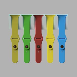 May include: A display of five colorful watch bands in yellow, green, red, yellow, and blue. Each band is secured with a dark brown clasp and is mounted on a white holder. The bands are made of a flexible material.