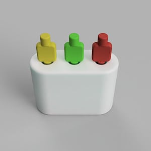 Puede incluir: Tres pequeñas figuritas, una amarilla, una verde y una roja, están de pie en un soporte blanco. El soporte tiene tres ranuras para las figuritas.