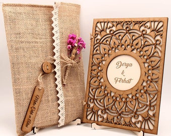 Pode incluir: Um convite de casamento de madeira com um design de corte a laser e os nomes "Derya & Ferhat" no centro. O convite é exibido em um pequeno suporte de madeira. O convite é embalado em um envelope de juta com uma borda de renda e um pequeno buquê de flores cor-de-rosa.