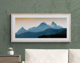 May include: A framed photograph of a mountain range with a blue and gray color scheme. The mountains are silhouetted against a light orange sky.
