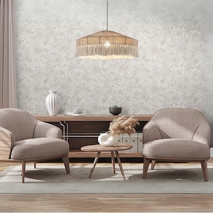 May include: A living room scene featuring two beige armchairs, a wooden coffee table, and a wooden cabinet. A large, round pendant light with a woven shade and fringe hangs from the ceiling. The walls have a textured, light gray pattern.