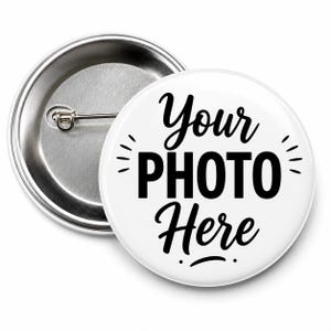 May include: A circular pin-back button with a white front featuring the black text Your PHOTO Here and small decorative lines. The back of the button is metallic silver with a horizontal pin mechanism for attachment to clothing or fabric items.