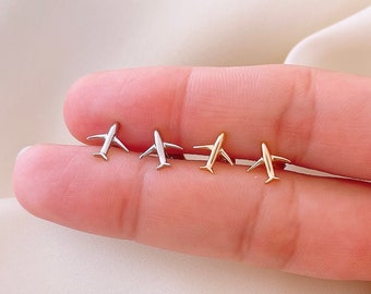 May include: Four airplane stud earrings in silver and gold. The earrings are small and delicate, perfect for everyday wear.