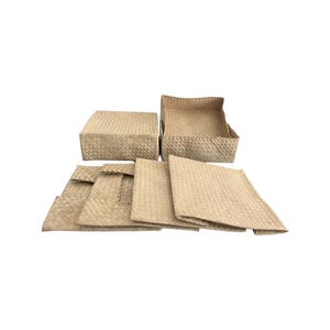 May include: A collection of woven natural fiber storage items. The set includes two rectangular boxes, one with a lid, and several matching placemats. The items are a light tan color and have a textured, woven appearance.